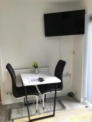 a table with two chairs and a television on a wall at The Old Grain Store Bed & Breakfast in Pidley