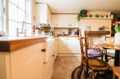 a kitchen with white cabinets and a table and a sink at Beautifully Designed Cottage Free WiFi in Rivenhall