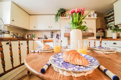 a table with a plate of bread and glasses of orange juice at Beautifully Designed Cottage Free WiFi in Rivenhall