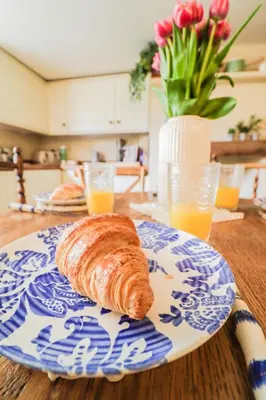 a croissant on a blue and white plate on a table at Beautifully Designed Cottage Free WiFi in Rivenhall