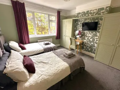 a hotel room with two beds and a television at The Tudors Modern 3-Bed Home with Fast WiFi, Private Drive & Near Town Center in Chelmsford