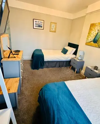 a hotel room with two beds and a desk at The Tudors Modern 3-Bed Home with Fast WiFi, Private Drive & Near Town Center in Chelmsford