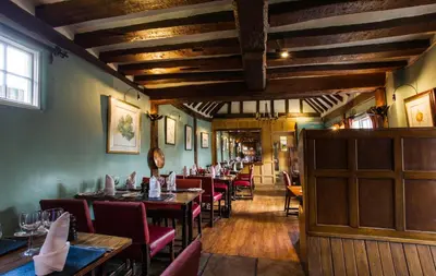 a restaurant with wooden ceilings and tables and chairs at The Bell Inn Hotel in Horndon on the Hill