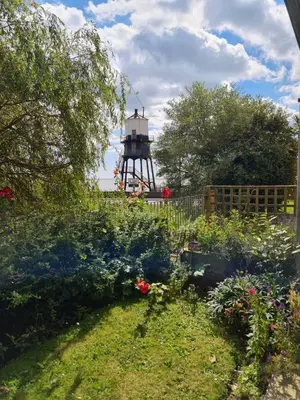 a garden with a lighthouse in the background at Alices’s Beachside Haven in Harwich