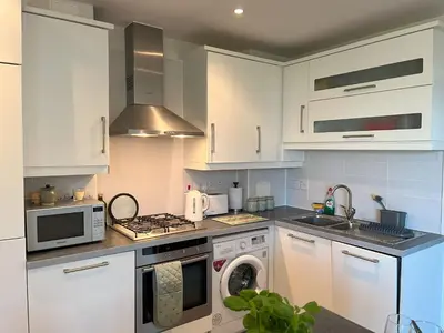 a kitchen with white cabinets and a washer and dryer at Alices’s Beachside Haven in Harwich