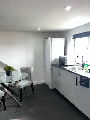 a kitchen with a table and a sink and a refrigerator at Modern Studio Flat In A Guest House In Basildon in Basildon