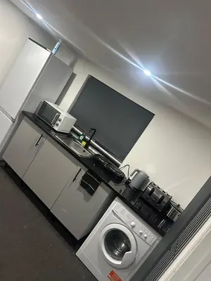 a kitchen with a tv and a washing machine at Modern Studio Flat In A Guest House In Basildon in Basildon
