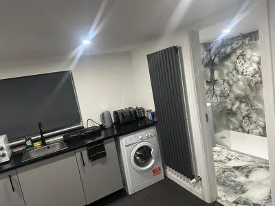 a laundry room with a washing machine and a tv at Modern Studio Flat In A Guest House In Basildon in Basildon