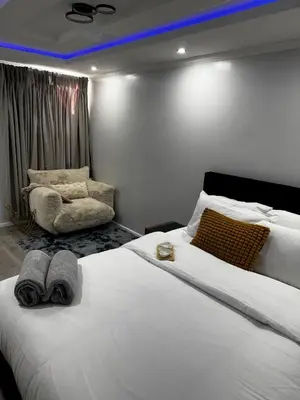a bedroom with a large white bed and a chair at Paramount Luxe Loft- 3 bedrooms, 4 beds cosy home in Laindon