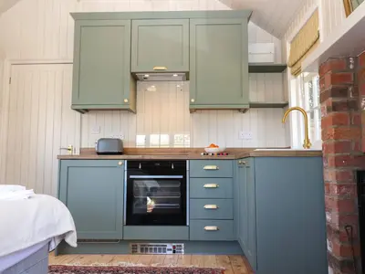 a kitchen with green cabinets and an oven at The Woodshed in Clacton-on-Sea