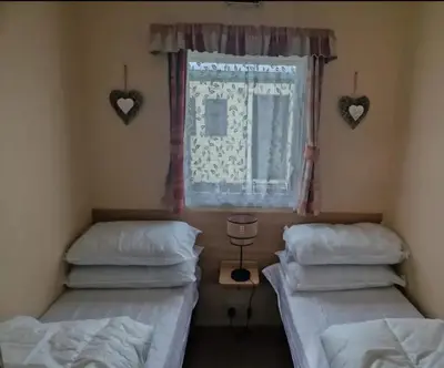 two beds in a room with a window and hearts on the wall at House of Eminence Holidays in Saint Osyth