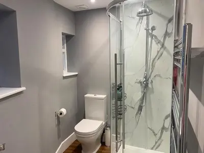 a bathroom with a toilet and a glass shower at The Old King Bill in Fenstanton