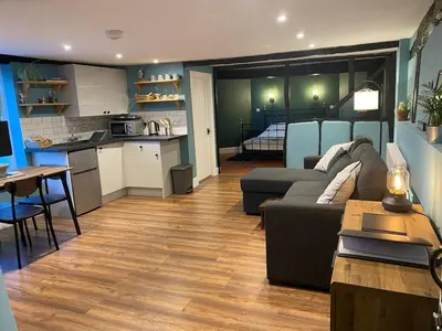 a living room with a couch and a table and a kitchen at The Old King Bill in Fenstanton