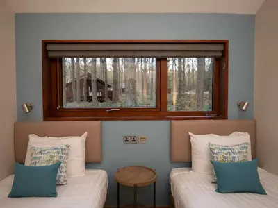 two beds in a room with a window at Thorpe Forest Cabins - Forest Holidays in Thetford