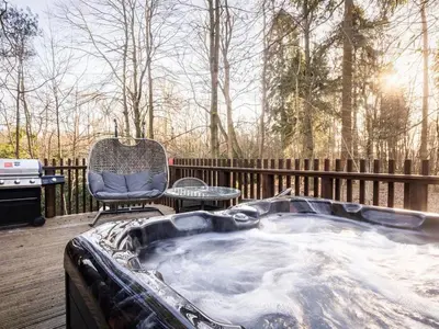 a jacuzzi tub on a deck with a chair at Thorpe Forest Cabins - Forest Holidays in Thetford