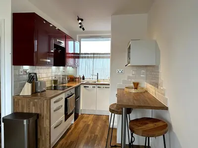 a kitchen with white cabinets and a wooden counter top at Flat-on-Sea in Southend-on-Sea