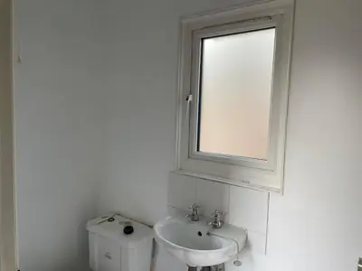 a white bathroom with a sink and a window at Barn conversion Corner Annexe in Earls Colne
