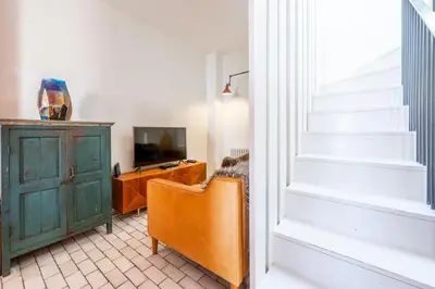 a living room with a staircase and a television at Edinburgh House in Aldeburgh