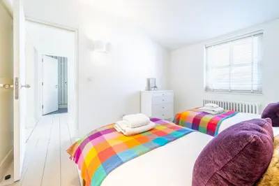a bedroom with two beds and a rainbow blanket at Edinburgh House in Aldeburgh