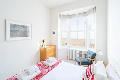 a bedroom with a bed and a chair and a window at Edinburgh House in Aldeburgh