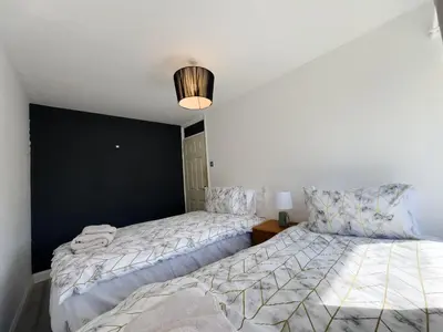 a bedroom with two beds and a black wall at Basildon Retreat Cozy 3-Bedroom Home in Basildon