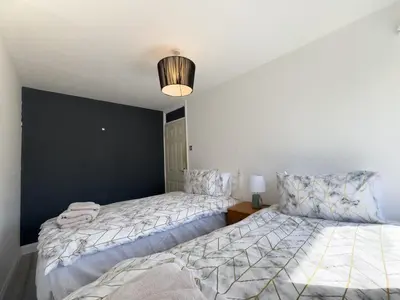 a bedroom with two beds and a black accent wall at Basildon Retreat Cozy 3-Bedroom Home in Basildon