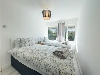 a white bedroom with two beds and a window at Basildon Retreat Cozy 3-Bedroom Home in Basildon
