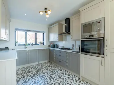 a kitchen with white cabinets and a tile floor at Hawkwell Hideaway Large 4 bedroom Home Hockley - Pass the Keys in Hawkwell