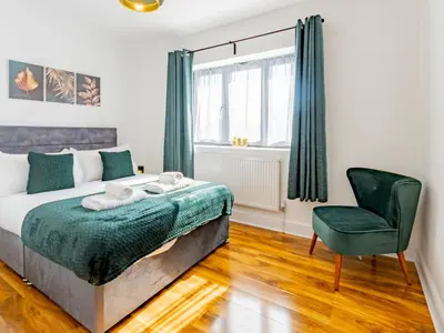 a bedroom with a bed and a chair at Hawkwell Hideaway Large 4 bedroom Home Hockley - Pass the Keys in Hawkwell
