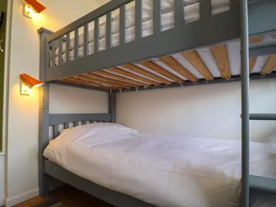 a bedroom with two bunk beds with white sheets at The Orchard Close Art House in Great Livermere