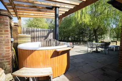a wooden bath tub sitting under a wooden pergola at Tewinbury Farm Hotel in Tewin
