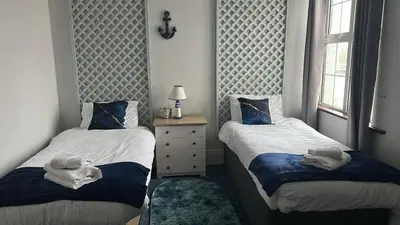 a bedroom with two beds and a dresser and a window at Seaside Escape in Thorpe Bay