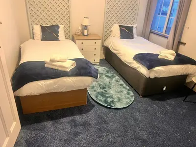 a bedroom with two beds and a table and a mirror at Seaside Escape in Thorpe Bay