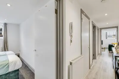 a white room with a bed and a hallway at Stylish stay Ware town with parking in Ware