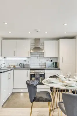 a kitchen with white cabinets and a table and chairs at Stylish stay Ware town with parking in Ware