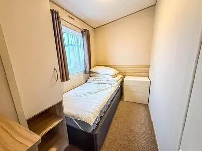 a small bedroom with a bed and a window at 6 Berth Caravan With Side Decking At Suffolk Sands Holiday Park Ref 45054C in Felixstowe