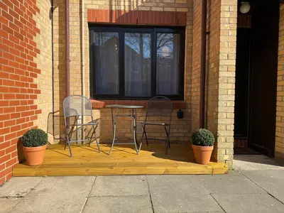 two chairs and a table on a porch with plants at The Tetris Retreat in Cambridge