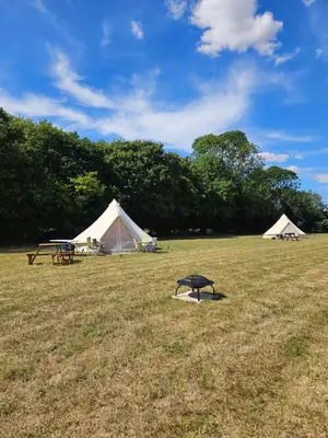 a field with two tents and a picnic table at Readers Field Glamping in Great Sampford