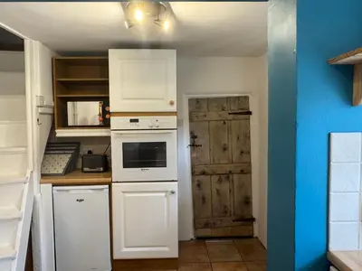 a kitchen with white appliances and a wooden door at Cosy Little Cottage in Woodbridge