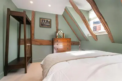 a bedroom with a bed and a wooden dresser at Ruperts Cottage in Coggeshall
