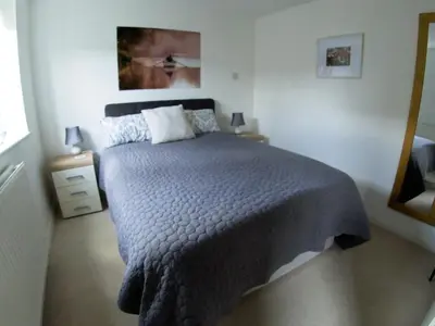 a bedroom with a bed with a gray comforter at The Nest in Needingworth