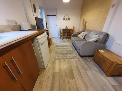 a living room with a couch and a kitchen at The Nest in Needingworth