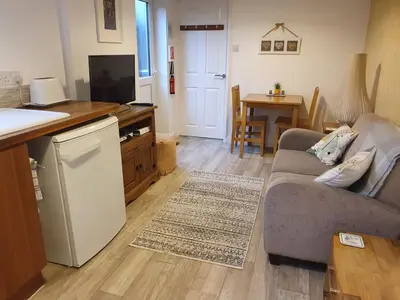 a living room with a couch and a kitchen at The Nest in Needingworth