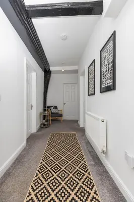a hallway with white walls and a black and white rug at Brandon Apartment in Town Centre with parking in Brandon