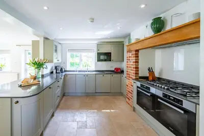 a kitchen with white cabinets and a brick wall at Marvellous secluded forest lodge - Stone Hall in Eyke