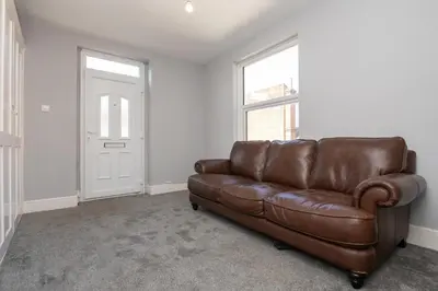 a brown leather couch in a living room with a window at The Harwich Hideaway in Harwich