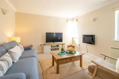 a living room with a blue couch and a table at 3 St Johns Court - Aldeburgh Coastal Cottages in Aldeburgh