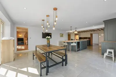 a living room with a table and a kitchen at Bakers Cottage, Blackmore End in Gosfield