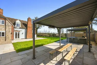a pavilion with a picnic table and benches on a patio at Bakers Cottage, Blackmore End in Gosfield