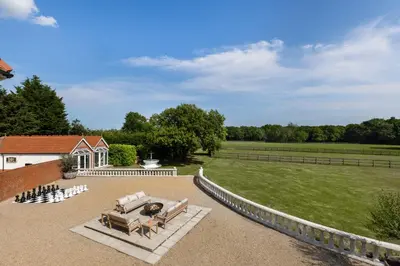 a patio with a couch and a grass field at Merry Lakes - Luxury Lakeside Escape with Pool - Just 30 Minutes from London in Hutton